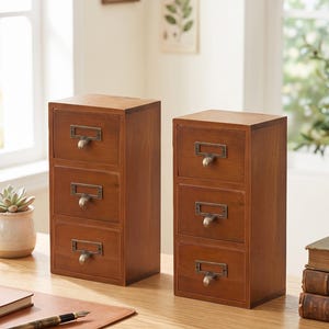 May include: Two wooden storage units, each featuring three stacked drawers with metal label holders and curved pulls. The text 2Pcs is visible in the upper right corner. These organizers have a medium brown wood finish and a vertical rectangular shape.