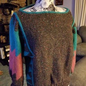 May include: A brown, teal, and pink knit sweater with a geometric pattern. The sweater has a boat neck and long sleeves.