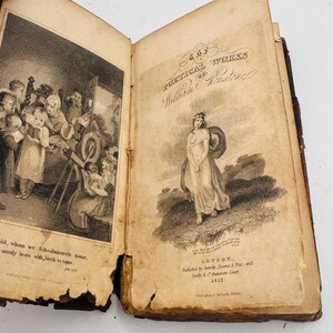 May include: Open antique book with aged, yellowed pages. The left page features a detailed black and white illustration of a school scene. The right page displays the title "POETICAL WORKS of William Wordsworth" and a drawing of a woman in a flowing gown.