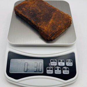 May include: A small, antique book with a worn, brown leather cover is placed on a digital scale. The scale displays a weight of 3.0 oz. The book's pages are visible, and the overall aesthetic suggests age and use.