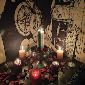 May include: A mystical scene featuring lit candles of various colors, including red, orange, and green, arranged with dried rose petals and stones. A silver chalice holds candles, and a pentagram and hand illustration are visible in the background. The scene evokes a spiritual or ritualistic theme.