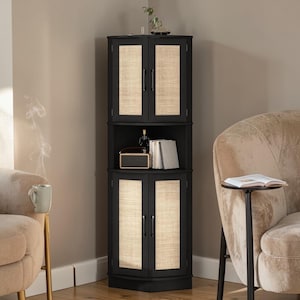 May include: A black corner cabinet with woven panels on the doors. The cabinet has three sections, with a shelf in the middle. A small radio, books, and a bottle are on the shelf. The cabinet is in a living room setting.