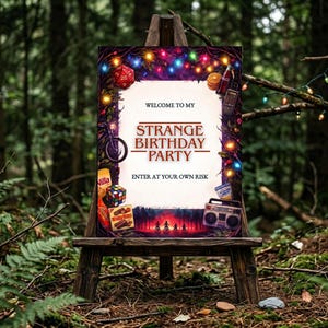 May include: A wooden easel displays a party sign with the text "Welcome to my Strange Birthday Party." The sign is decorated with colourful lights, a red die, a Rubik's Cube, and other themed elements. The background is a forest.
