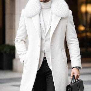 May include: A white overcoat with a fur collar, worn over a matching vest and turtleneck. The outfit is completed with black pants and a black leather briefcase. A watch is visible on the wrist.