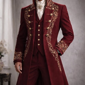 Puede incluir: Un traje de tres piezas burdeos con detalles bordados en oro. El abrigo largo presenta patrones ornamentados en los bordes y las mangas, con botones dorados. El chaleco y el pantalón completan el conjunto, creando un look formal y elegante.