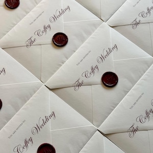 May include: A collection of cream-coloured wedding invitations, each sealed with a burgundy wax seal. The invitations are arranged in a grid. The text "The Coffey Wedding" and "You are invited to" are printed in burgundy script.