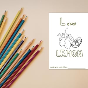 May include: A white rectangular coloring page featuring a line drawing of two lemons on a branch and a lemon slice. The text reads L IS FOR LEMON and MADE WITH LOVE FROM. A collection of multi-colored sharpened pencils is arranged to the left.