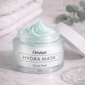 May include: A jar of Orivion Hydra Mask facial peel with a light blue, creamy product. The jar is open, with the lid resting beside it. The label reads "Hydra Mask Facial Peel" and "50G". A white towel is in the background.
