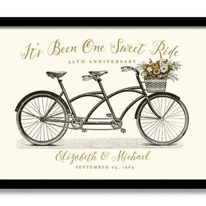 May include: A black and white illustration of a tandem bicycle with a basket of flowers on the back. The text "It's Been One Sweet Ride" is above the bicycle, and "50th Anniversary" is below. The names "Elizabeth & Michael" and the date "September 23, 1969" are at the bottom of the image.