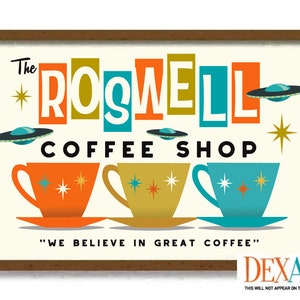 May include: A framed retro-style sign for "The Roswell Coffee Shop." The sign features colorful text and illustrations of flying saucers and coffee cups. The phrase "WE BELIEVE IN GREAT COFFEE" is also included.