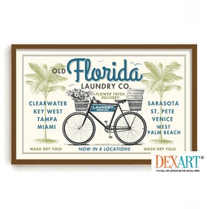 May include: A vintage-style illustration of a bicycle with baskets delivering laundry. The text reads "Old Florida Laundry Co." and lists locations including Clearwater, Key West, Tampa, Miami, Sarasota, St. Pete, Venice, West Palm Beach. The text also says "Flower Fresh Delivery" and "Wash Dry Fold".
