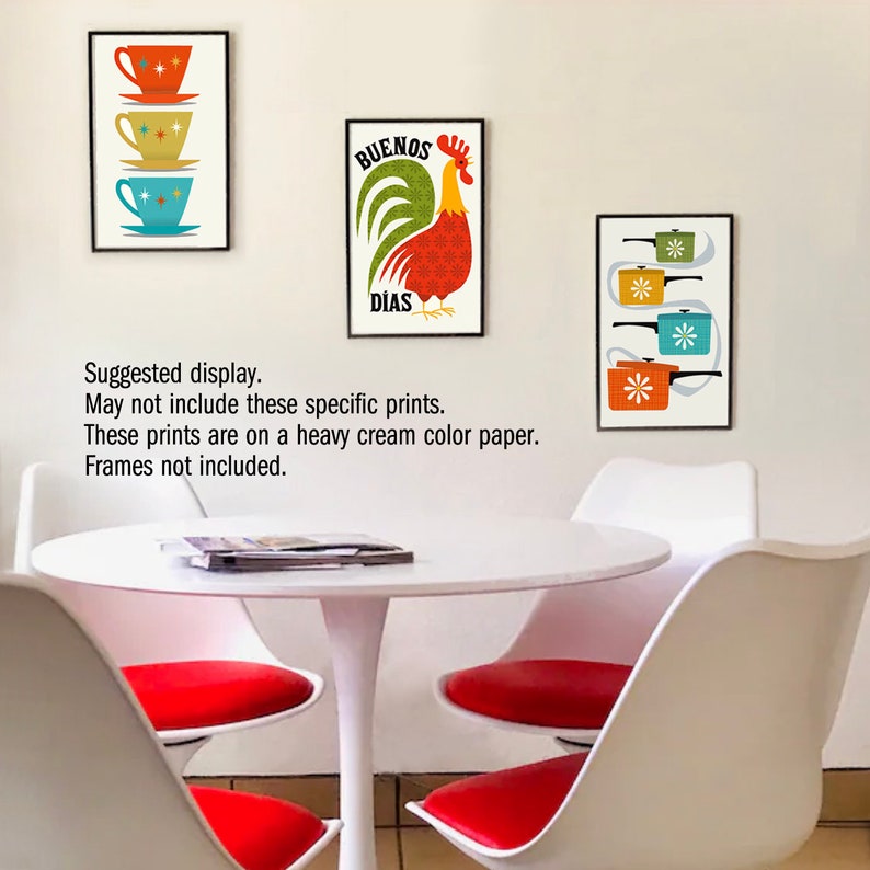 May include: Three framed prints with a mid-century modern aesthetic. The prints feature a rooster with the text "Buenos Dias", a stack of teacups, and a stack of pots. The prints are displayed on a white wall above a white table with red chairs.