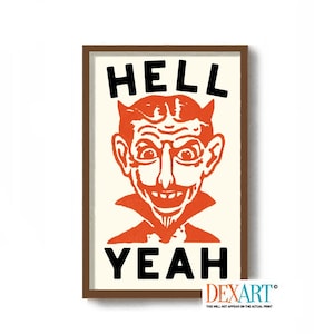 May include: Framed print featuring a vintage illustration of a devil with the words "HELL YEAH" in bold black letters. The devil is depicted in orange with a sinister grin and horns, set against a cream background.