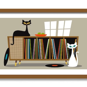 K&ouml;nnte beinhalten: Ein Retro-Schallplattenspieler-Schrank mit einer schwarzen Katze, die oben sitzt, und einer wei&szlig;en Katze, die davor steht. Der Schrank hat einen Holzrahmen und ist mit bunten Schallplatten gef&uuml;llt. Auf dem Boden liegen zwei schwarze Schallplatten.