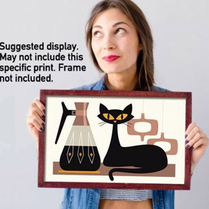 May include: A mid-century modern style print featuring a black cat with yellow eyes, a coffee pot, and abstract shapes in shades of brown, beige, and black.