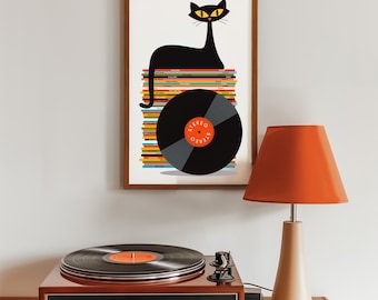 May include: A framed art print featuring a black cat perched atop a stack of colorful vinyl records. A large vinyl record is in the foreground. A vintage record player and an orange lamp are on a wooden surface.