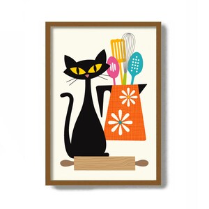 May include: A black cat with yellow eyes stands next to a pitcher with a floral print and a rolling pin. The pitcher is filled with colorful kitchen utensils, including a whisk, a spatula, and spoons.