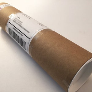 May include: A brown cardboard tube with a white end cap. A white label with the text "USPS TRACKING # - EP" is attached to the tube.