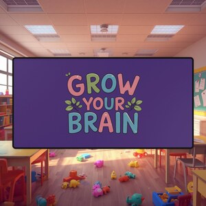 Może przedstawiać: Duży fioletowy znak z napisem "GROW YOUR BRAIN" w kolorowych literach. Znak znajduje się w klasie, otoczony zabawkami na podłodze i stołach.