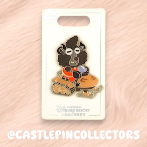 Könnte beinhalten: Ein Shanghai Disney Resort Emaille-Pin mit einer schwarzen, lockigen Figur, die eine Brille und eine orangefarbene Jacke trägt und auf einem orangefarbenen Schneemobil mit Kettenantrieb fährt. Der Pin ist auf einer weißen, rechteckigen Karte befestigt.