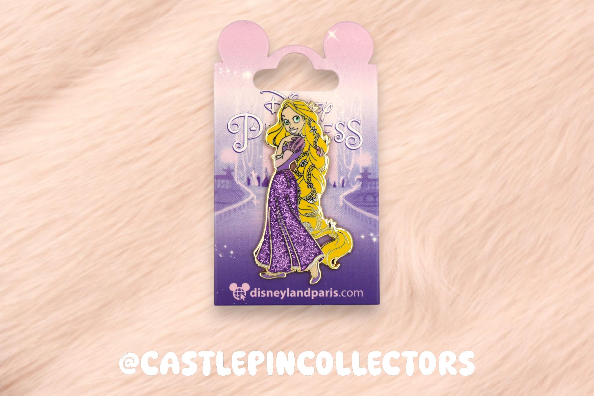 May include: A Disney Princess enamel pin featuring Rapunzel with long yellow hair and a purple dress. The pin is on a purple backing card with the word "Princess" and the Disneyland Paris logo.