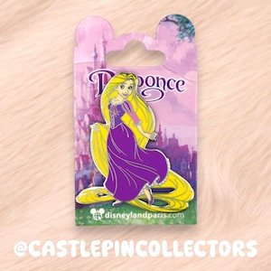 Könnte beinhalten: Anstecknadel mit Rapunzel aus Disneys Tangled, in einem lila Kleid mit langen gelben Haaren. Die Anstecknadel befindet sich auf einer rosa Rückwandkarte mit dem Disneyland Paris-Logo und dem Wort "Rapunzel". Der Hintergrund ist ein rosa Schloss.
