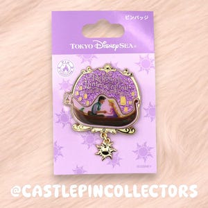 May include: A Tokyo DisneySea pin featuring Rapunzel and Flynn Rider in a boat, set against a purple glitter background with floating lanterns. The pin has a gold frame and a dangling sun charm, mounted on a purple card with sun icons.