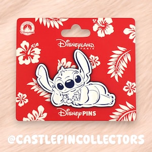 May include: A Disney pin featuring the character Stitch, in white, on a red background with white floral designs. The pin is on a red backing card with the Disneyland Paris logo and the words "Disney Pins".