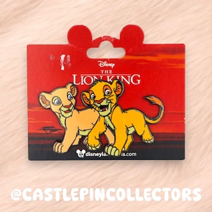 May include: A Disney pin featuring Simba and Nala from The Lion King. The pin is on a red backing card with the movie title and Disney logo. The pin has a Mickey Mouse ear-shaped top.