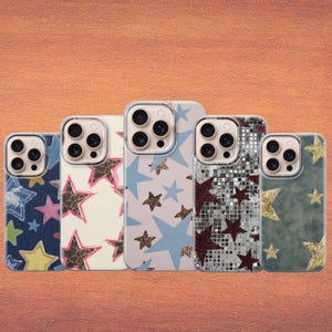 Op de afbeelding: Vijf smartphonehoesjes op een rij. De eerste heeft een blauw spijkerstofpatroon met kleurrijke sterren. De tweede is crème met sterren in luipaardprint. De derde is lichtblauw met bruine glittersterren. De vierde heeft een zilveren discobalpatroon met donkerrode sterren. De vijfde is donkergroen met gouden glittersterren.
