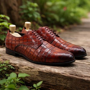 May include: A pair of brown leather dress shoes with a textured, crocodile-like pattern. The shoes have a classic lace-up design, dark brown laces, and black soles. Wooden shoe trees are inserted inside the shoes.