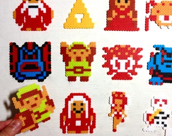 Arte retro del videojuego Legend of Zelda. Sprites de píxeles de 8 bits hechos con cuentas Perler. Imanes de NES. Link, el Viejo, Octoroc, la Trifuerza, Moblin.