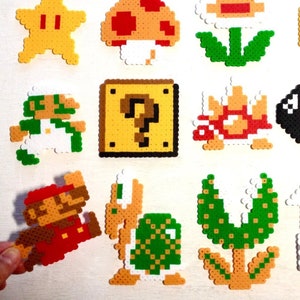 Puede incluir: Una colecci&oacute;n de personajes y objetos coloridos de pixel art de la serie de videojuegos Super Mario. Incluye a Mario, Luigi, una estrella, una seta, una moneda, Goomba, un bloque de interrogaci&oacute;n, Koopa Troopa, Bala Bill y m&aacute;s.