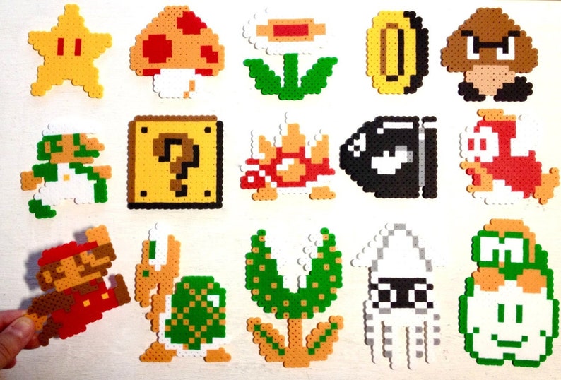 Puede incluir: Una colecci&oacute;n de personajes y objetos coloridos de pixel art de la serie de videojuegos Super Mario. Incluye a Mario, Luigi, una estrella, una seta, una moneda, Goomba, un bloque de interrogaci&oacute;n, Koopa Troopa, Bala Bill y m&aacute;s.