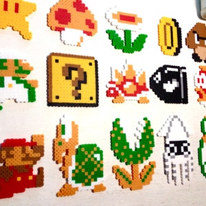 Puede incluir: Una colecci&oacute;n de personajes y objetos coloridos de pixel art de la serie de videojuegos Super Mario. Incluye a Mario, Luigi, una estrella, un hongo, una flor, una moneda, un Goomba, un bloque de interrogaci&oacute;n, un Koopa Troopa, un Bill Bala y m&aacute;s.
