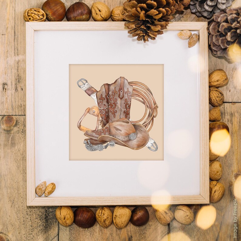 May include: Watercolor illustration of cowboy gear, including a brown cowboy hat, boots, and a lasso, set against a beige background. The boots have decorative stitching. The image is framed in a wooden frame.