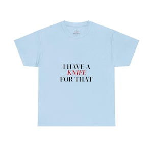 Puede incluir: Camiseta azul claro con el texto "I HAVE A KNIFE FOR THAT" en negro y rojo. La camiseta tiene cuello redondo y mangas cortas. El texto está centrado en la parte delantera de la camiseta.