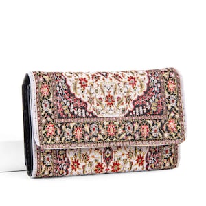 May include: A rectangular wallet with a colorful, patterned design. The wallet features a black border and a flap closure. The pattern includes red, gold, and black floral and geometric elements on a white background.