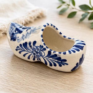 May include: A set of three ceramic mugs with a speckled, matte finish. The mugs are in shades of cream, light gray, and dark gray. Each mug has a simple, minimalist design and a rounded handle.