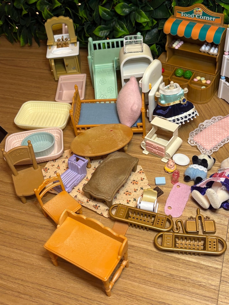 May include: A collection of miniature plastic dollhouse furniture and accessories, including a Food Corner shop stand, a bed with a pink pillow, a vanity, chairs, tables, a small bathtub, and various tiny household items in assorted colors.