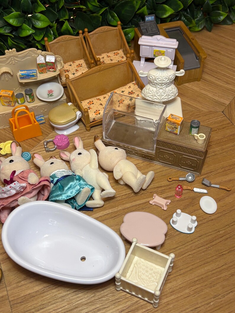 May include: A collection of miniature toy furniture and accessories including a white bathtub, a crib, two wooden benches with floral cushions, a shop counter, a cash register, and four flocked rabbit figures in various outfits and poses.