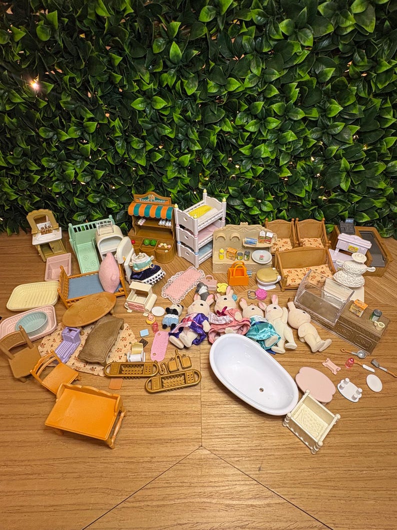 May include: A collection of miniature dollhouse furniture and accessories including a white bathtub, several small animal figures, beds, chairs, a food stand, and various household items like trays, tables, and kitchenware scattered across a surface.