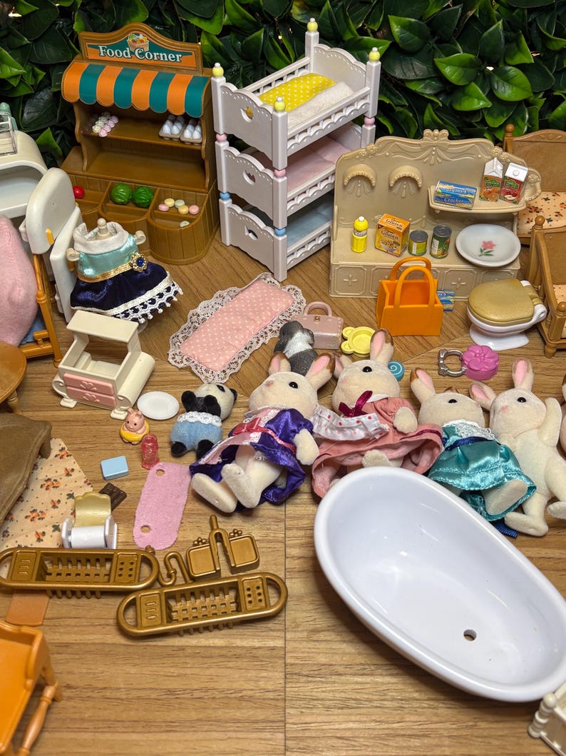 May include: A collection of miniature dollhouse furniture and animal figures, including a food corner stand, a white triple-bunk bed, a bathtub, and several rabbit figures dressed in fabric clothing, alongside various small accessories like bags and food items.