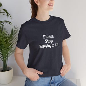 以下が含まれることがあります： 「Please Stop Replying to All」の白文字が入った濃いネイビーブルーのTシャツ。クルーネックのスタイルで、柔らかい素材で作られています。カジュアルウェアアイテムです。