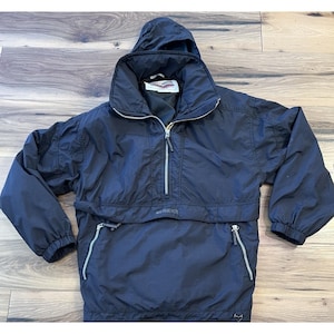 May include: A black anorak-style jacket with a hood and a half-zip closure. The jacket has two zippered pockets and elastic cuffs. The brand name "GERMEYER" is visible on the front. The jacket is made of a lightweight, possibly water-resistant material.