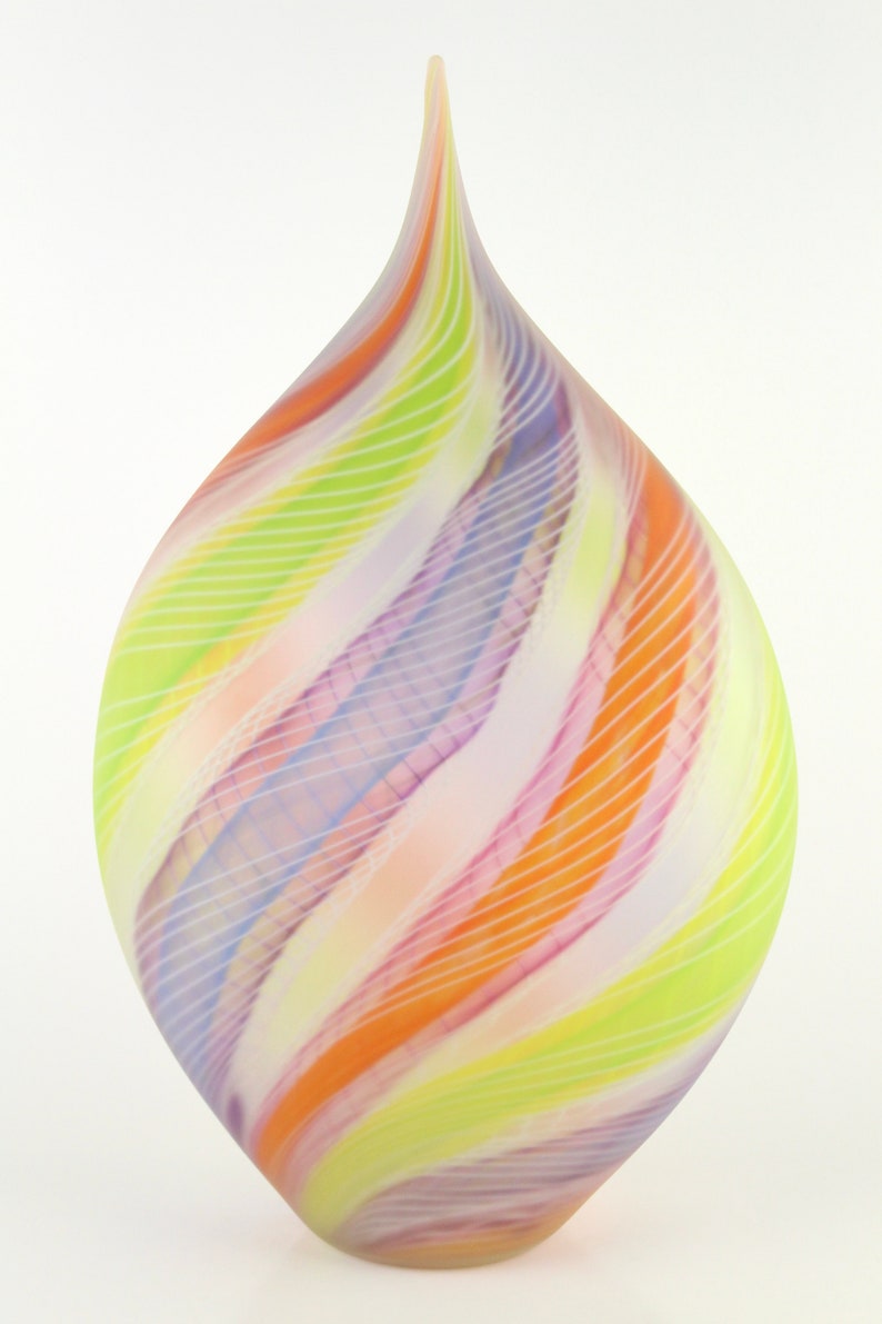 May include: A colorful glass vase with a teardrop shape. The vase features a swirl design of pastel colors including orange, pink, yellow, and purple. Thin white lines accent the design, creating a unique decorative piece.