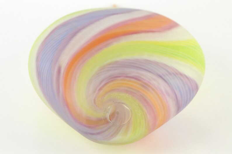 May include: A colorful, swirled glass ornament in shades of lavender, orange, white, and green. The glass has a spiral design and a small hole at the bottom. The ornament is likely for decoration.