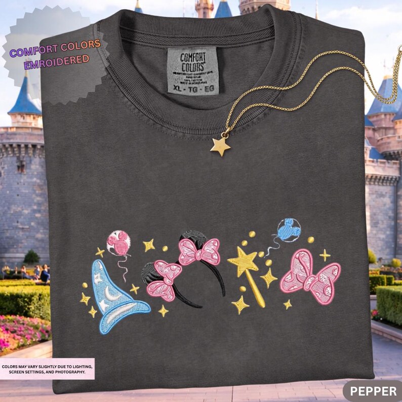 A black t-shirt with a colorful embroidered design featuring various Disney-themed elements such as a wizard hat, a wand, and a star.