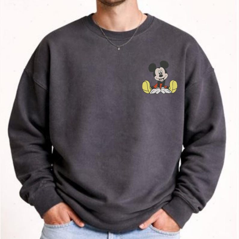 A man wearing a gray sweatshirt with a cartoon character printed on the front.