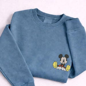 A blue sweatshirt with a cartoon character of Mickey Mouse printed on the front.
